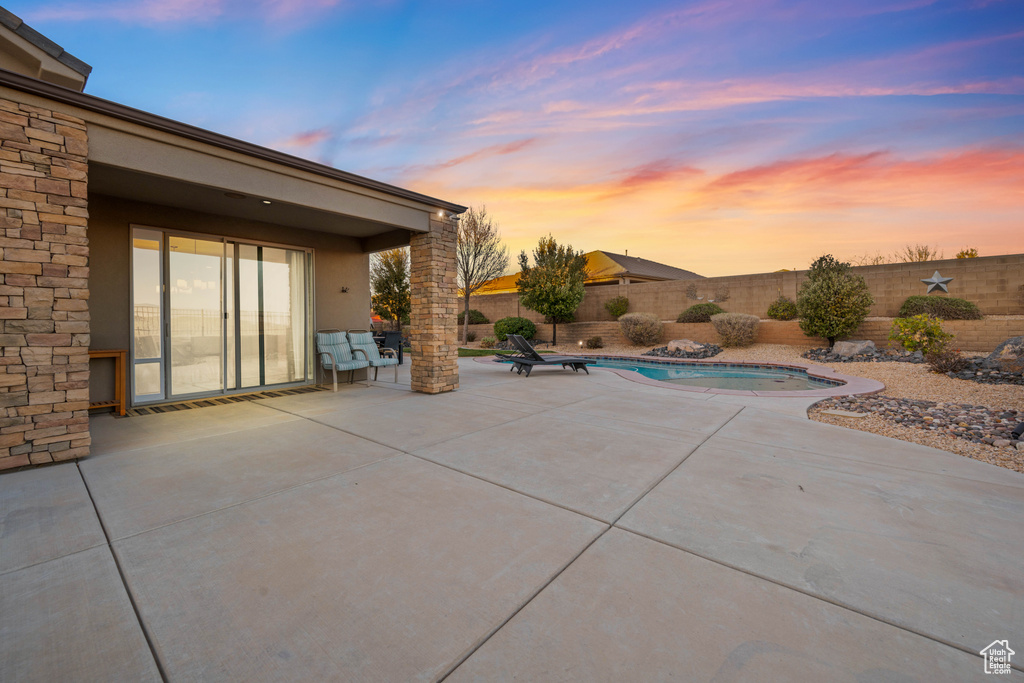 Patio terrace at dusk with a fenced in pool