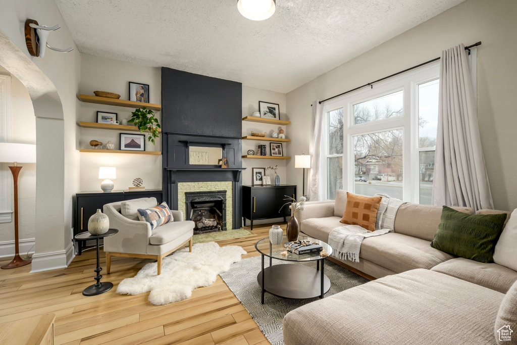 Living room with wood-type flooring, a textured ceiling, and a fireplace