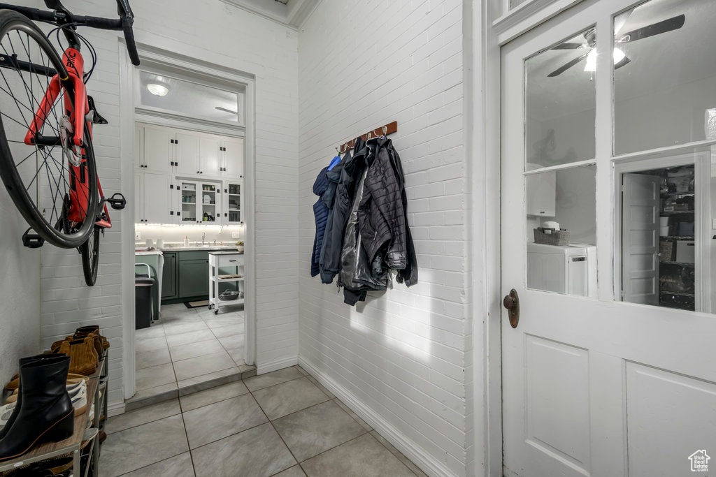 Interior space with ceiling fan, brick wall, separate washer and dryer, and light tile patterned floors