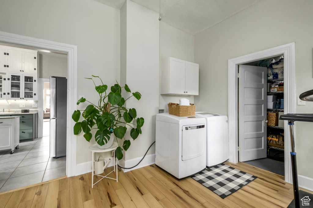 Laundry area featuring light hardwood / wood-style floors, cabinets, and washing machine and clothes dryer