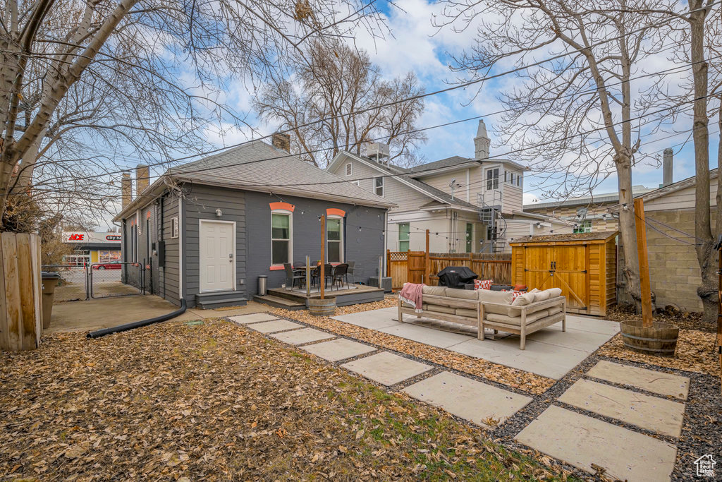 Rear view of house with an outdoor living space, an outbuilding, a patio area, and a wooden deck