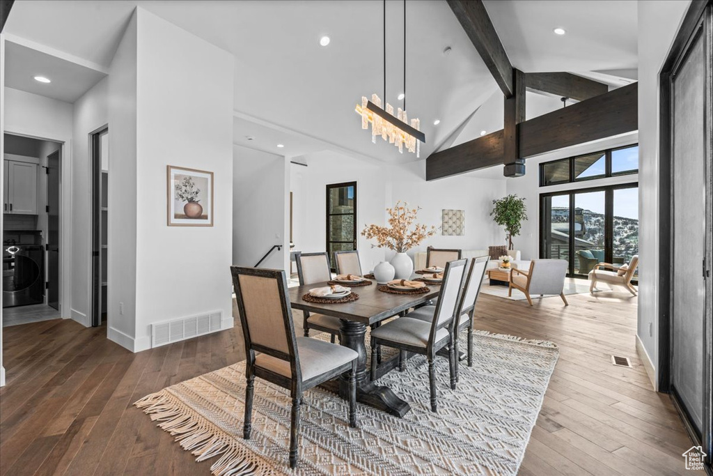 Dining space with beamed ceiling, wood-type flooring, washer / dryer, and high vaulted ceiling