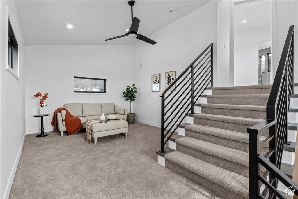 Living room with light carpet, high vaulted ceiling, and ceiling fan