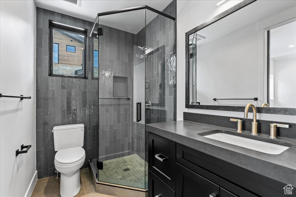 Bathroom featuring walk in shower, tile patterned floors, vanity, and toilet