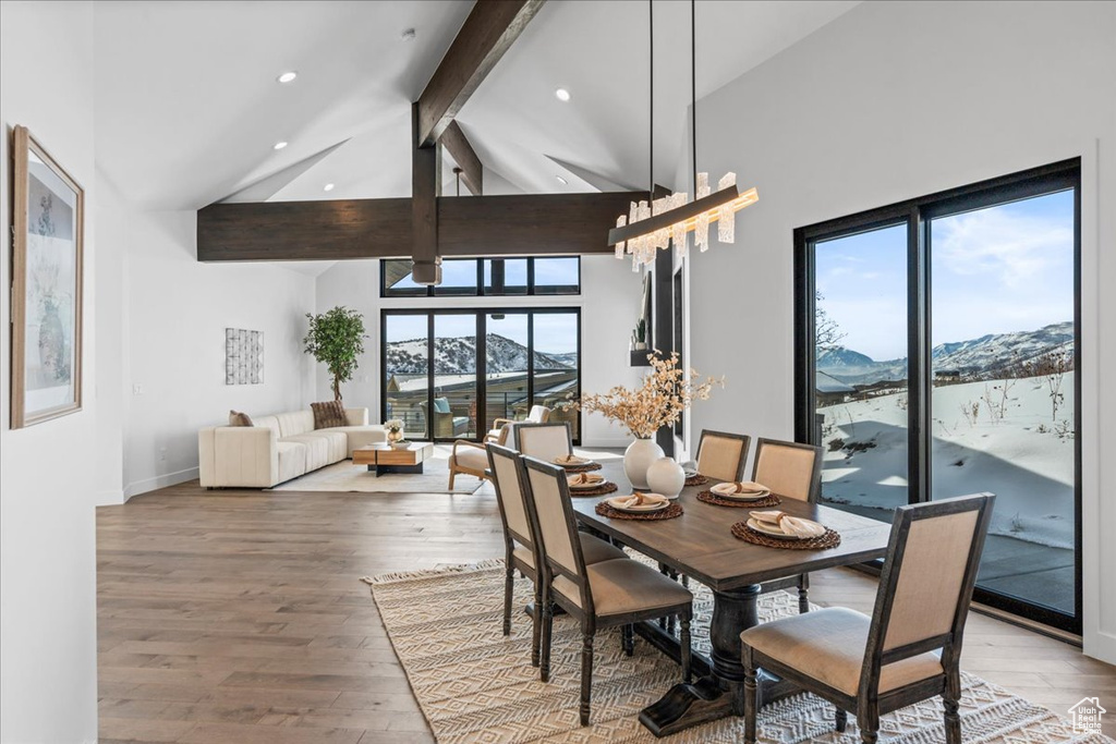 Dining space featuring a mountain view, beam ceiling, high vaulted ceiling, and hardwood / wood-style flooring