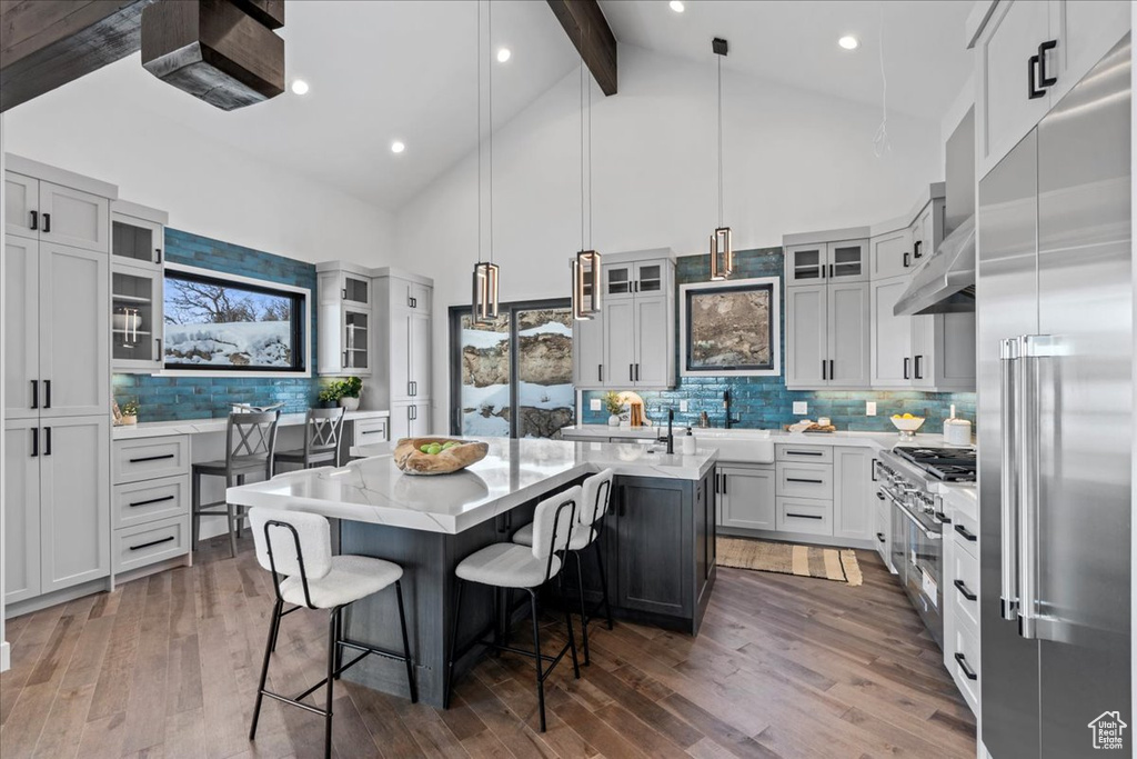 Kitchen with a kitchen island, beamed ceiling, a breakfast bar area, hanging light fixtures, and built in refrigerator