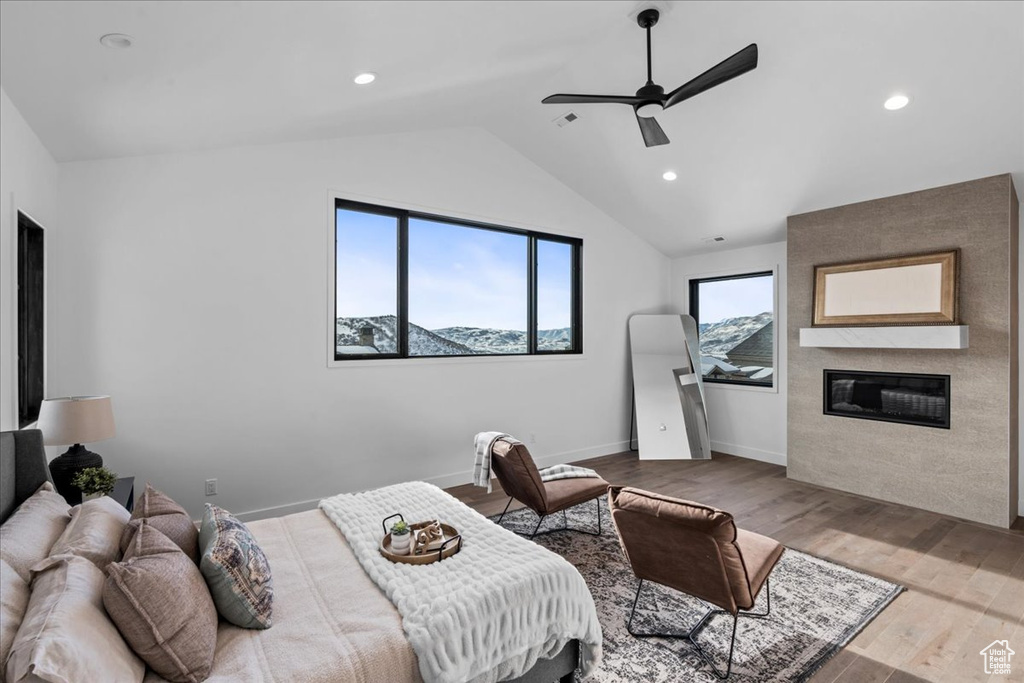 Bedroom featuring lofted ceiling, light wood-type flooring, a large fireplace, a mountain view, and ceiling fan