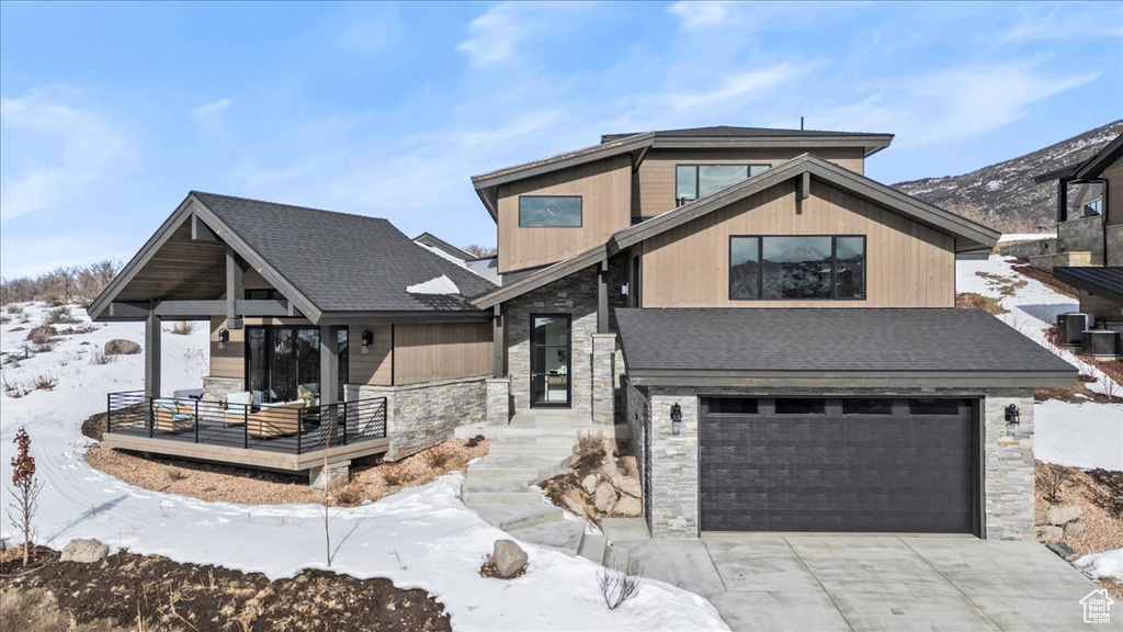 View of front of house with a garage, central air condition unit, and a porch