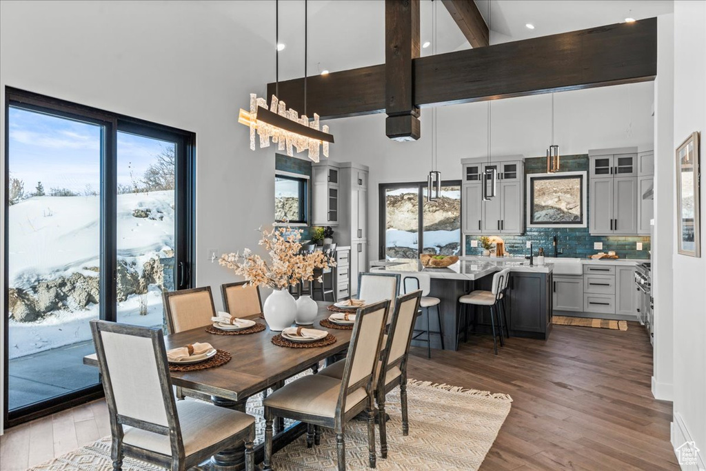 Dining area featuring hardwood / wood-style flooring, a towering ceiling, and beam ceiling