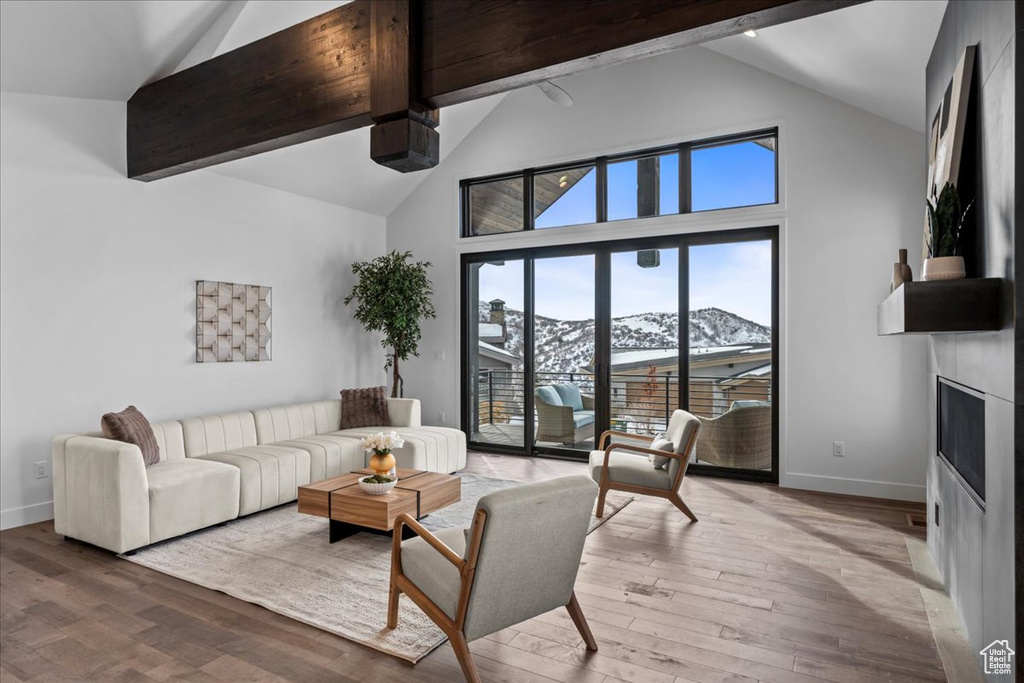 Living room featuring beamed ceiling, a mountain view, light wood-type flooring, and a fireplace