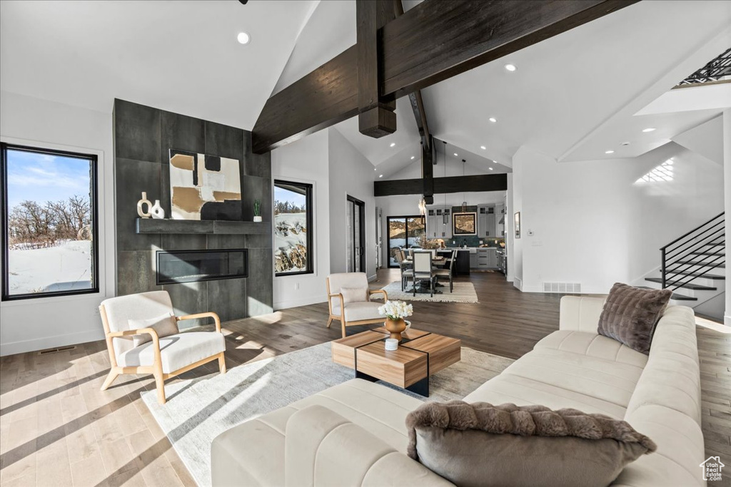 Living room with hardwood / wood-style floors, a fireplace, high vaulted ceiling, and beamed ceiling