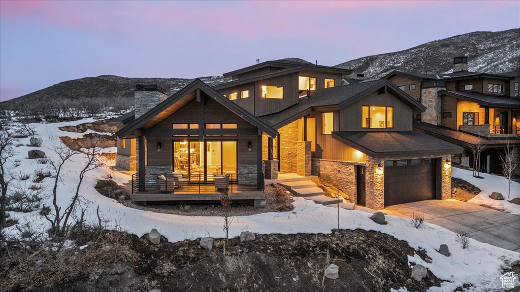 Snow covered property with a garage, a mountain view, and a porch