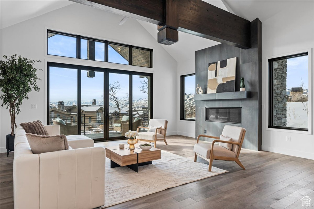 Living room featuring hardwood / wood-style floors, beam ceiling, a fireplace, and high vaulted ceiling