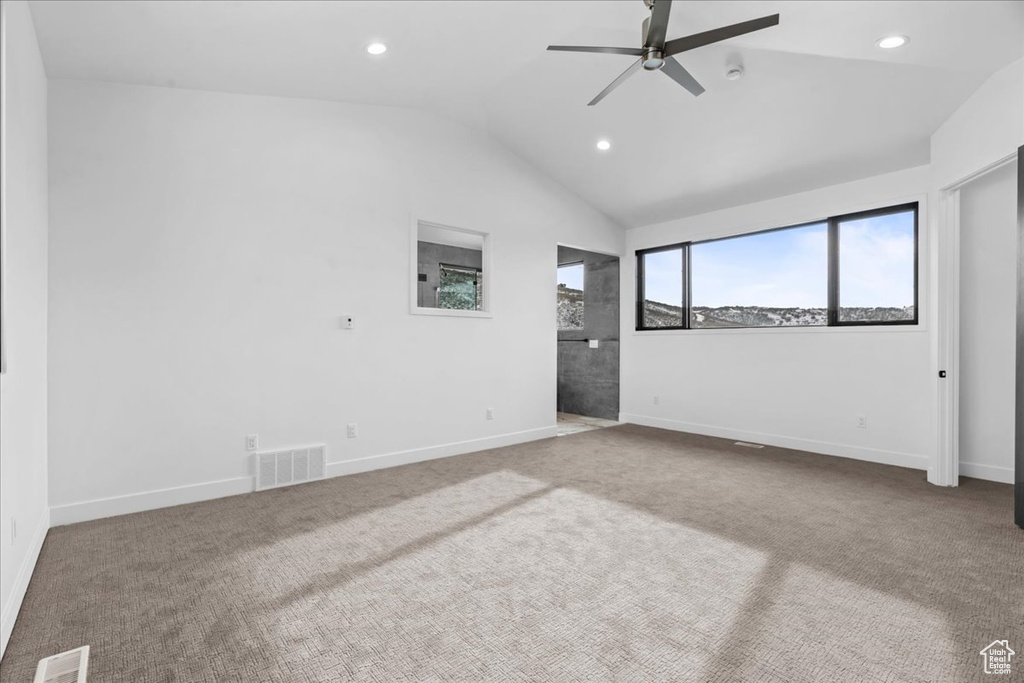 Empty room with vaulted ceiling, carpet flooring, and ceiling fan