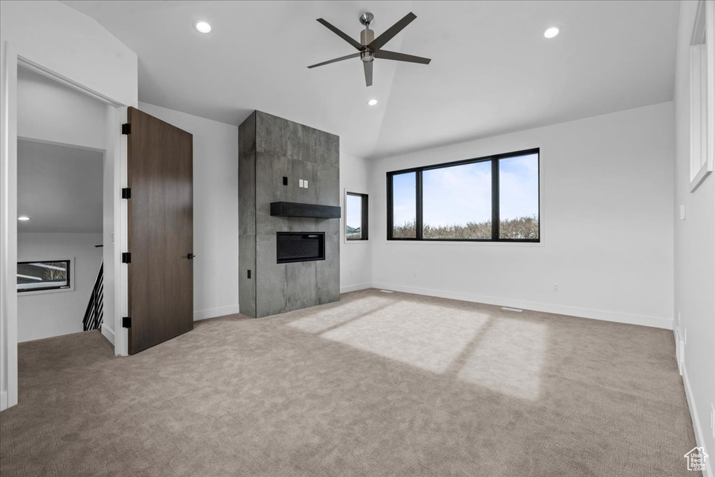 Unfurnished living room with high vaulted ceiling, a large fireplace, light colored carpet, and ceiling fan