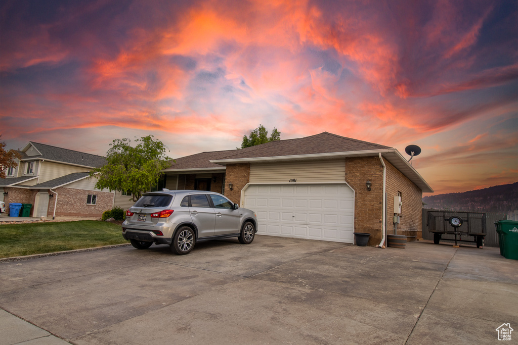 Single story home featuring brick siding, a garage, concrete driveway, and a yard