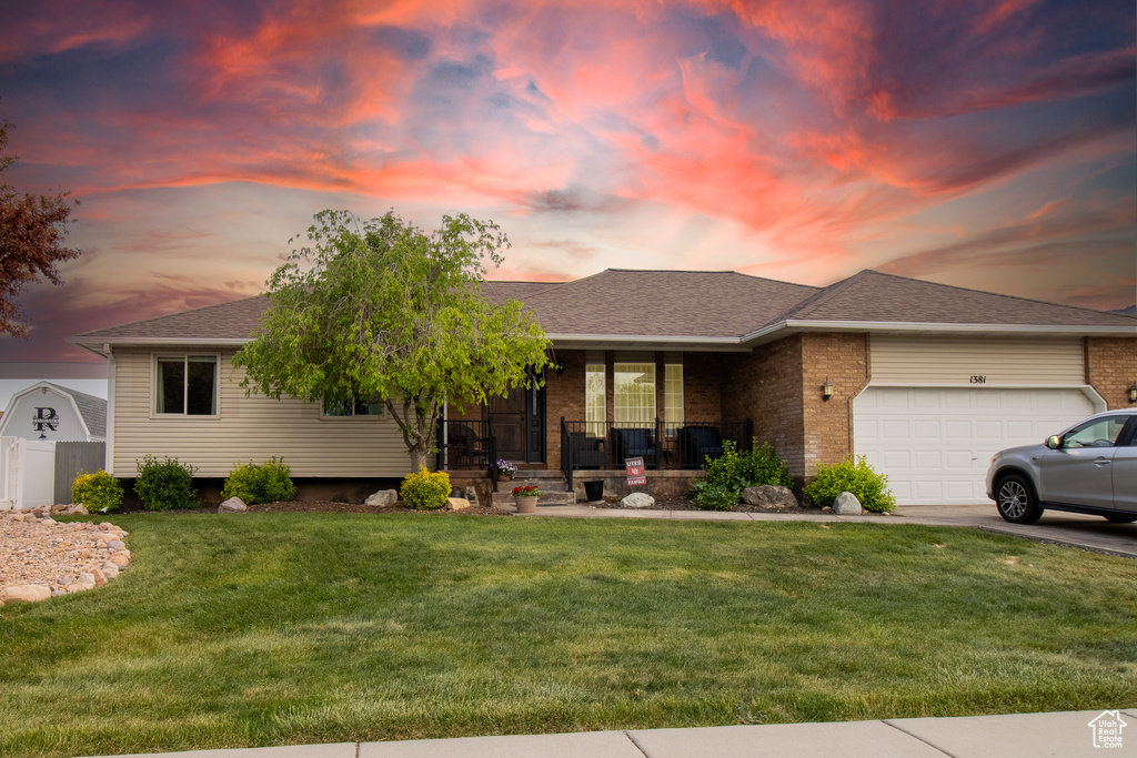 Ranch-style home with a porch, a front lawn, an attached garage, and brick siding