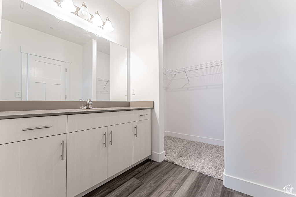 Bathroom featuring vanity, wood finished floors, and a walk in closet