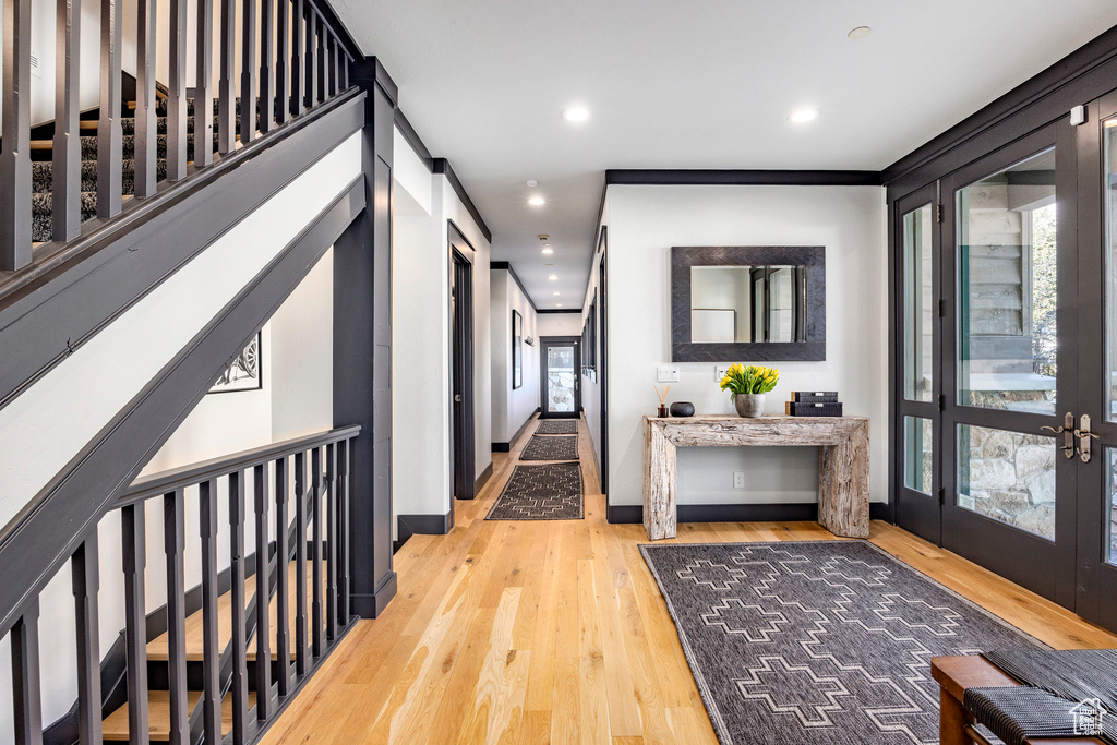 Hall with wood finished floors, recessed lighting, baseboards, french doors, and stairway
