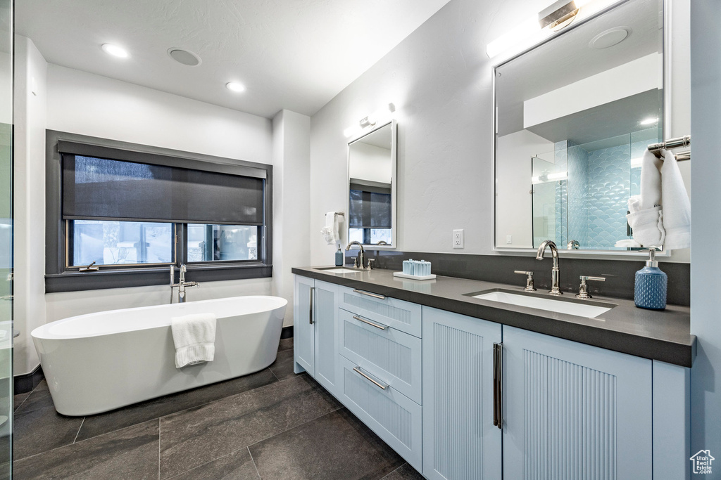 Bathroom with a soaking tub, double vanity, an enclosed shower, and recessed lighting