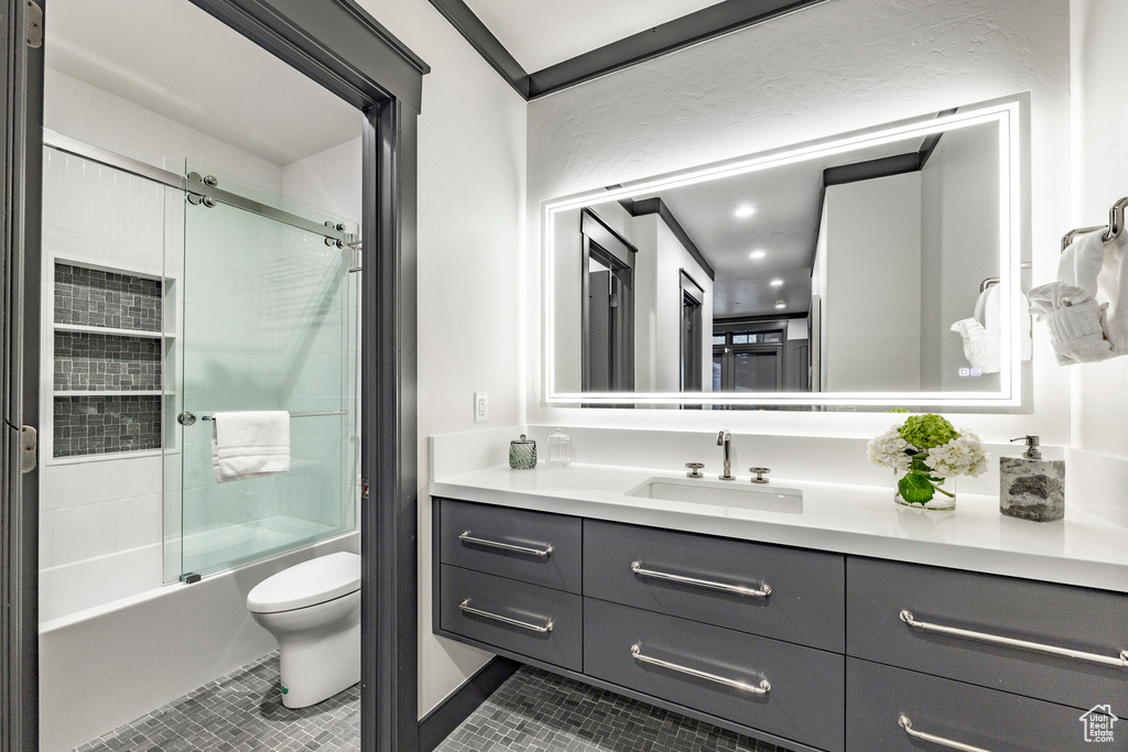 Full bathroom with tile patterned flooring, toilet, vanity, and shower / bath combination with glass door