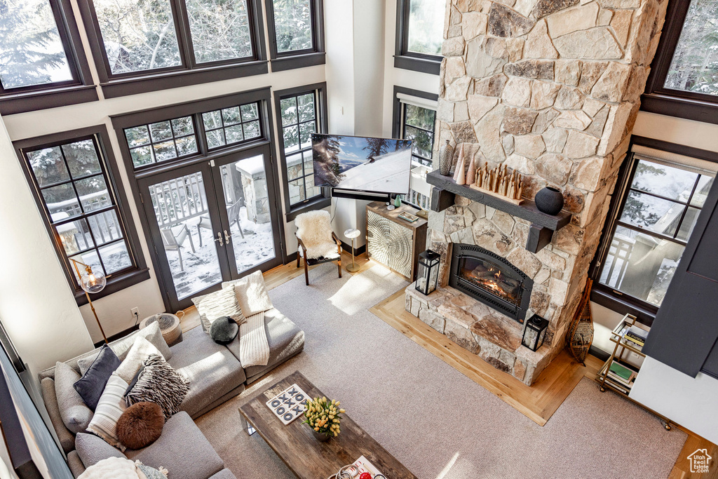 Living room featuring a stone fireplace, a high ceiling, french doors, and carpet floors
