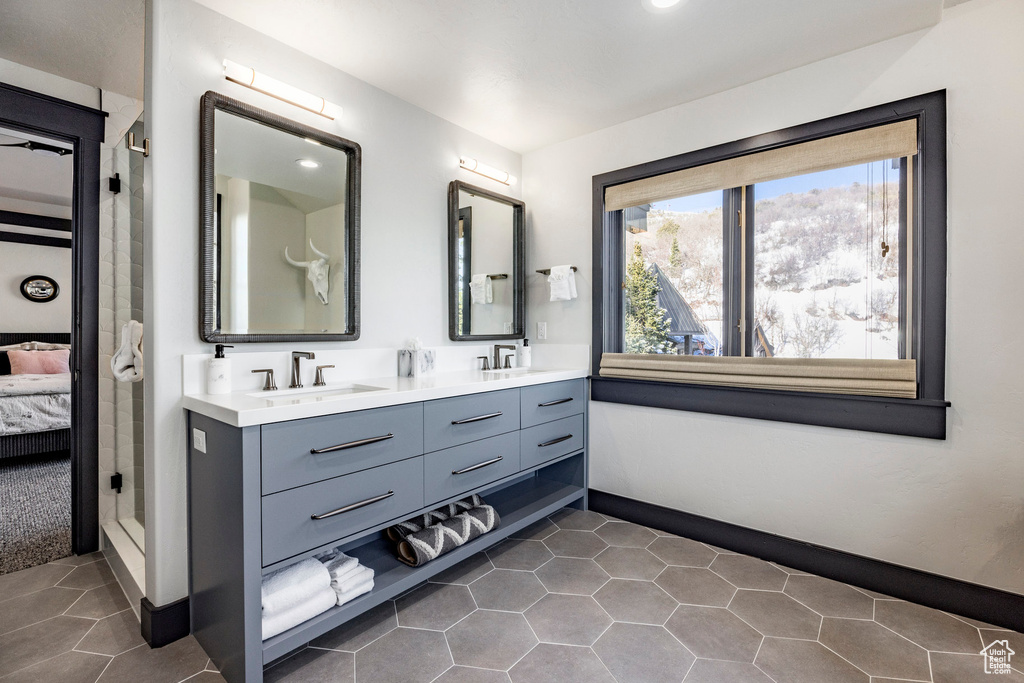 Ensuite bathroom with double vanity, baseboards, and tile patterned floors