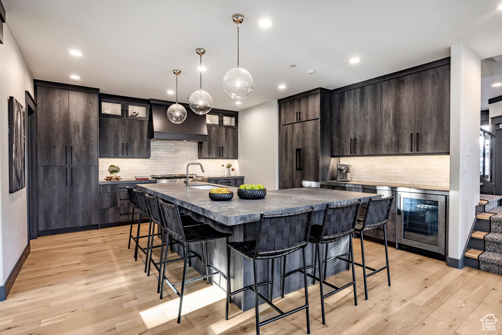 Kitchen featuring a kitchen bar, recessed lighting, dark countertops, light wood-style flooring, and tasteful backsplash