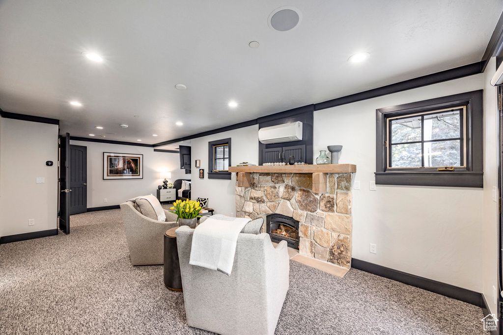 Living area with light colored carpet, recessed lighting, a wall mounted AC, baseboards, and a stone fireplace