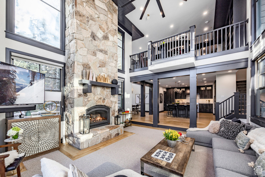 Living area with a towering ceiling, a stone fireplace, wood finished floors, stairway, and ornate columns