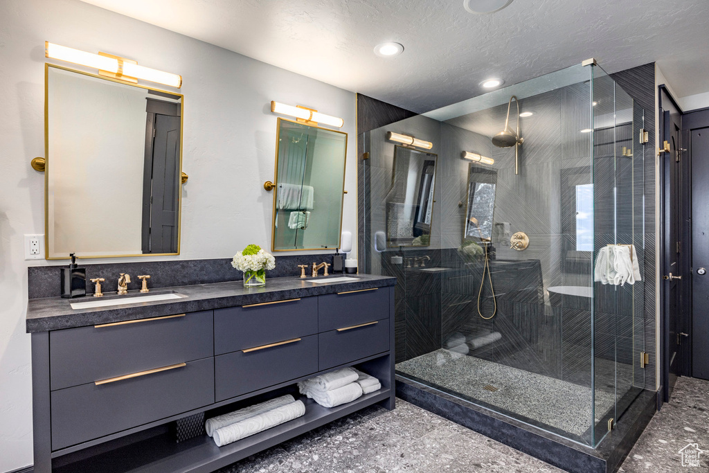 Full bathroom featuring a shower stall, double vanity, and recessed lighting