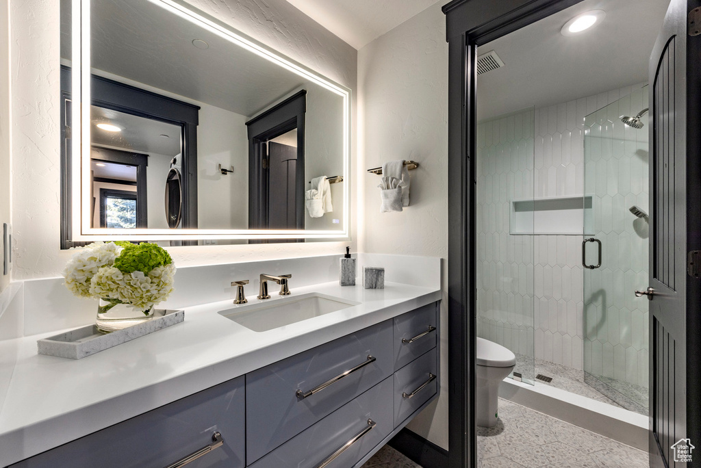 Bathroom with a stall shower, vanity, toilet, and recessed lighting