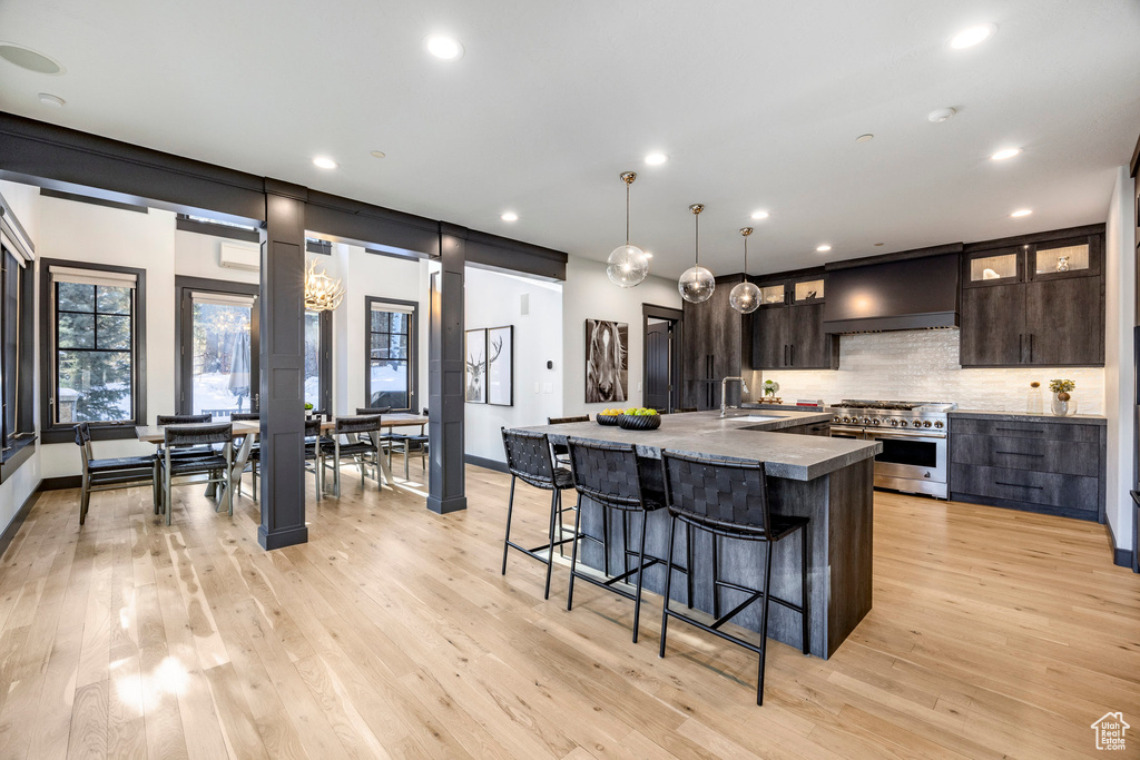 Kitchen with double oven range, dark brown cabinetry, decorative backsplash, recessed lighting, and a breakfast bar