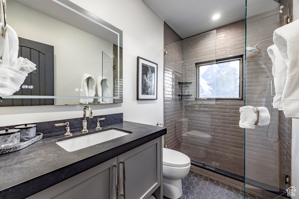 Bathroom with toilet, a stall shower, vanity, and tile patterned floors