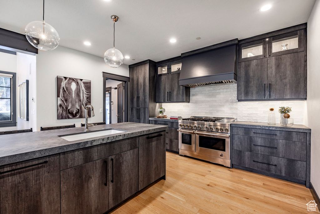 Kitchen featuring double oven range, a sink, custom range hood, pendant lighting, and backsplash