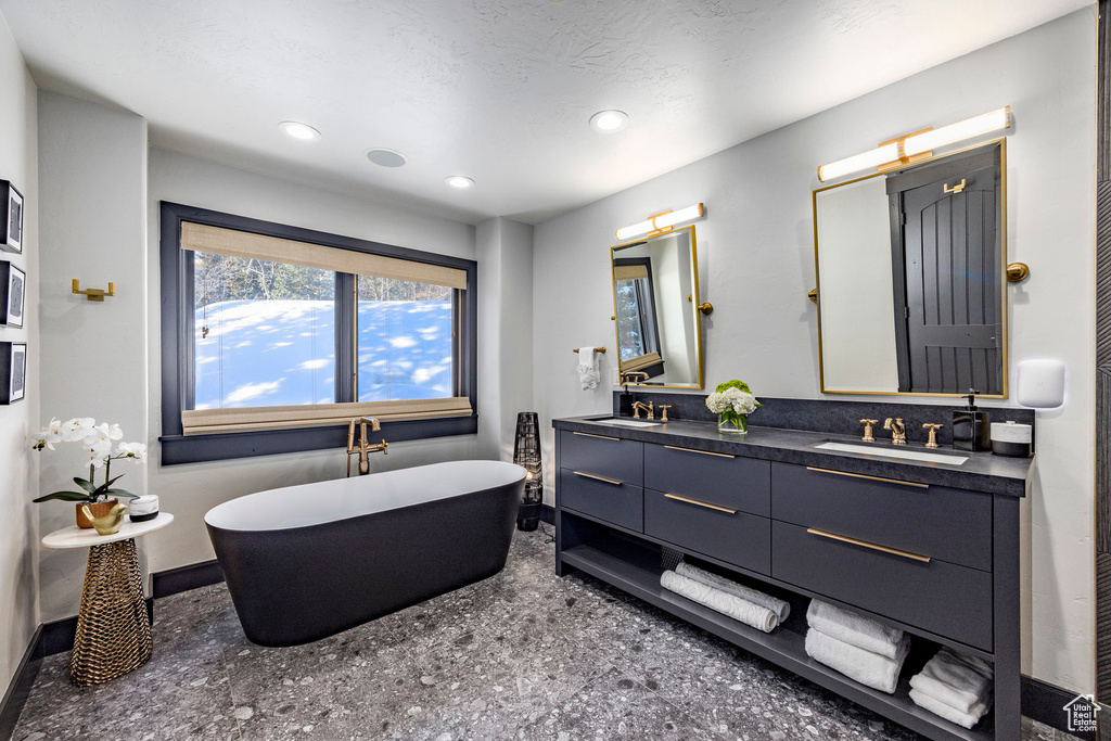 Full bath featuring baseboards, a soaking tub, double vanity, recessed lighting, and speckle patterned floor