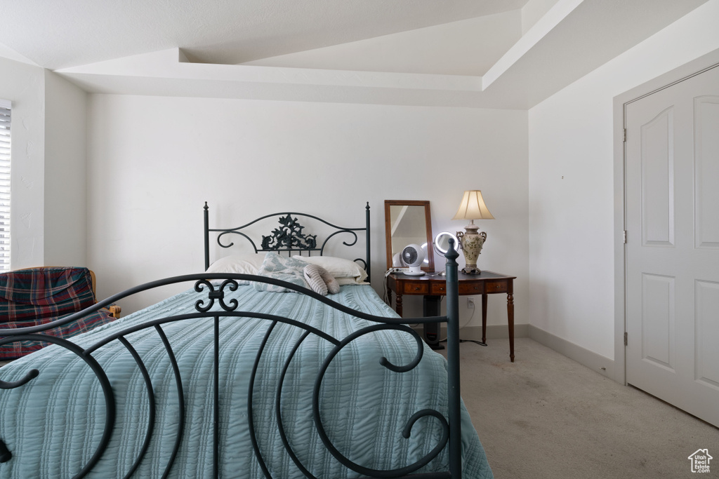 Bedroom with light carpet and lofted ceiling