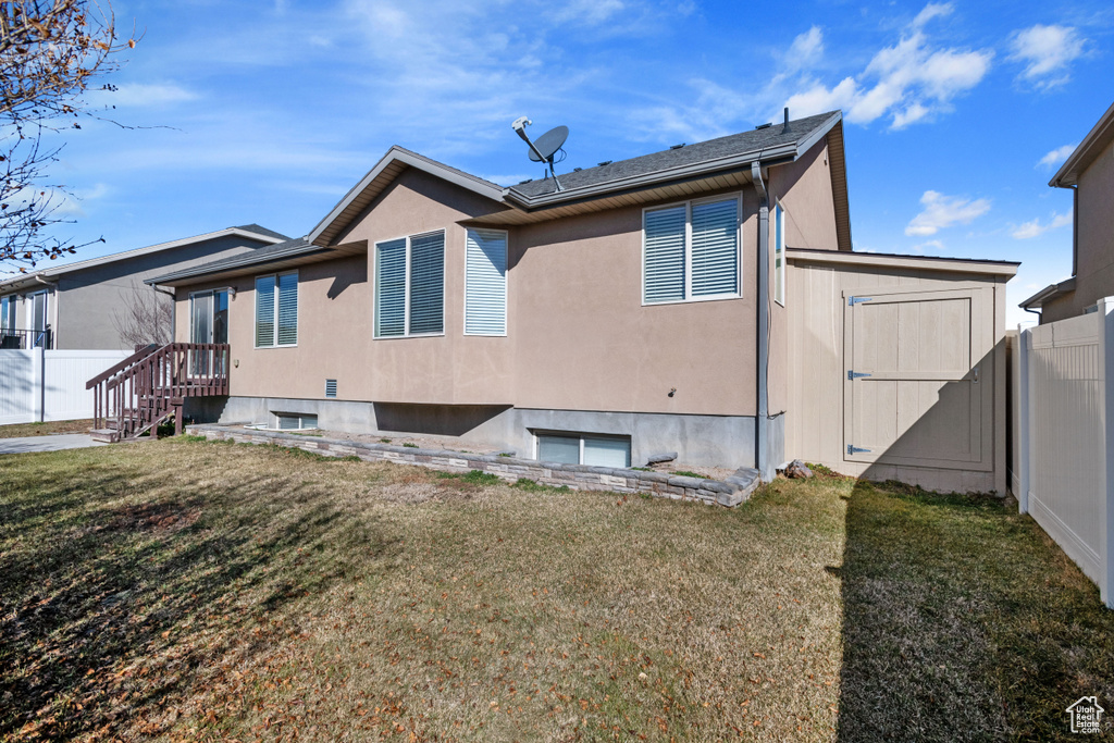 Back of house with a yard, fence, and stucco siding