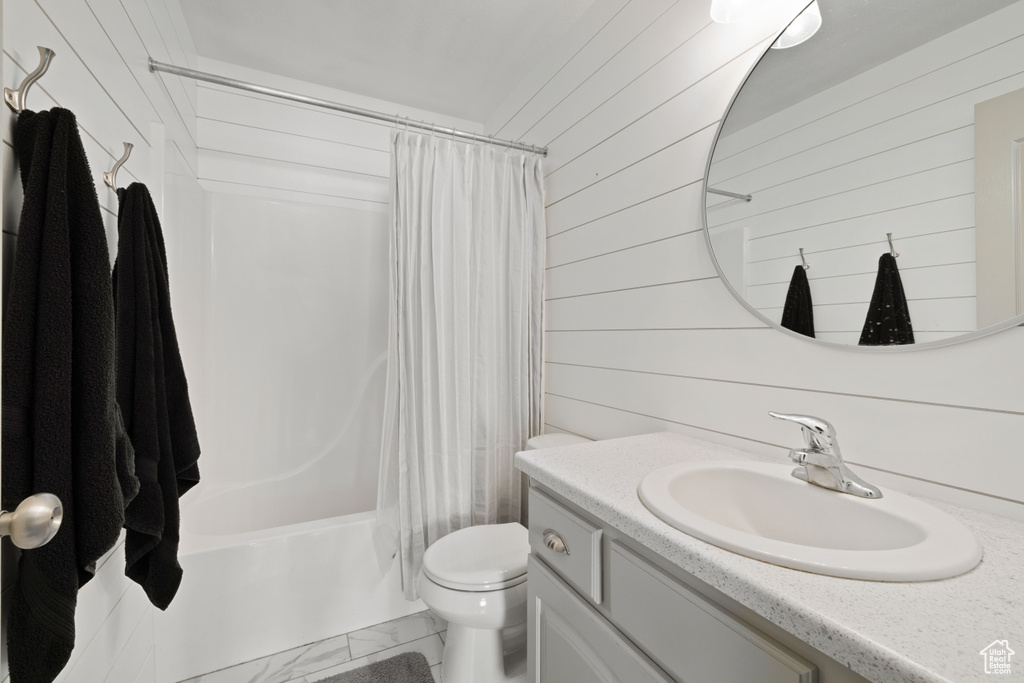 Full bathroom featuring shower / bath combo, vanity, wooden walls, and toilet