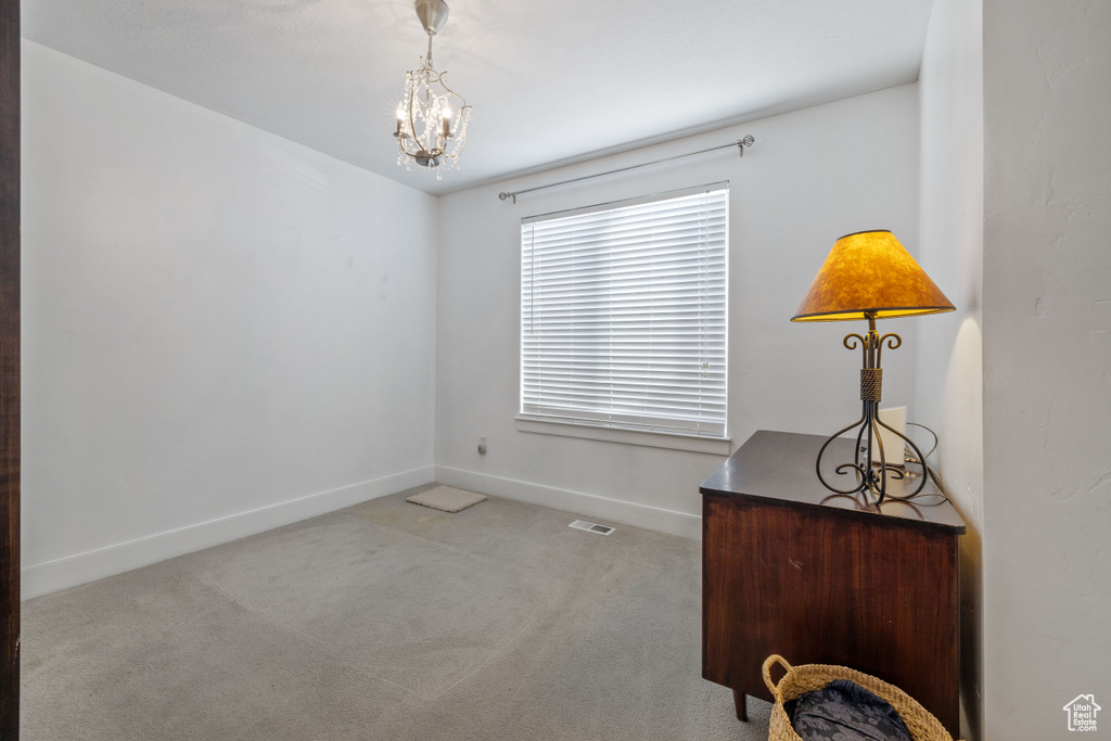 Carpeted spare room with an inviting chandelier
