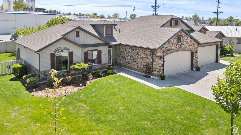 View of front of home with stone siding, an attached garage, driveway, and roof with shingles