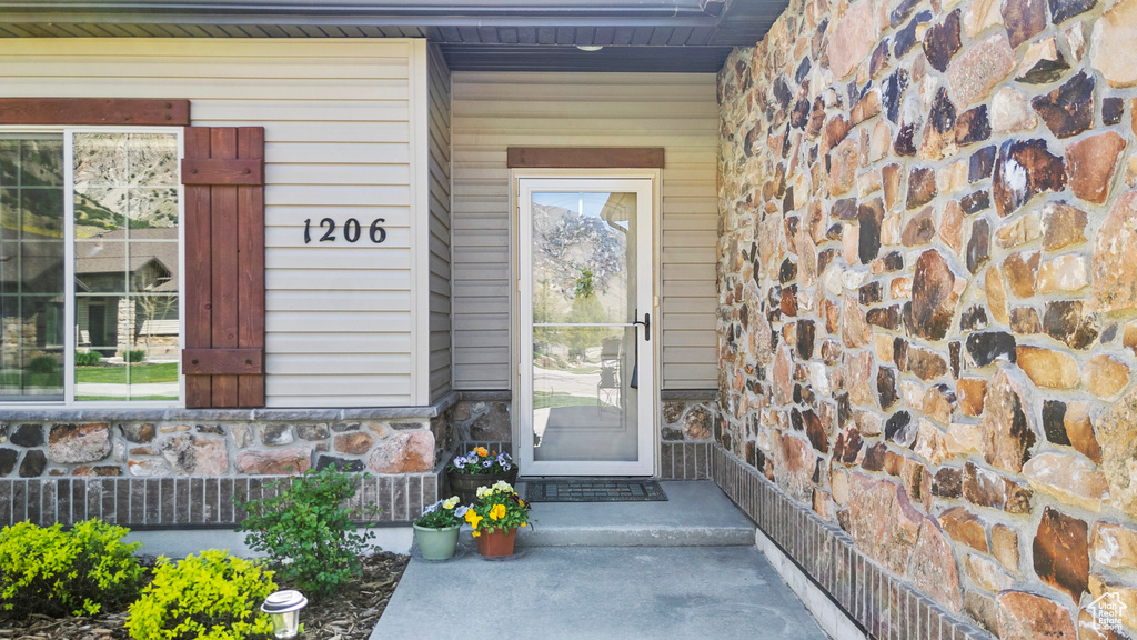 Doorway to property featuring stone siding and covered porch