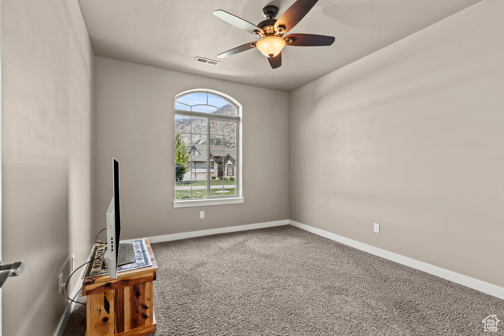 Spare room with carpet floors, a ceiling fan, and baseboards