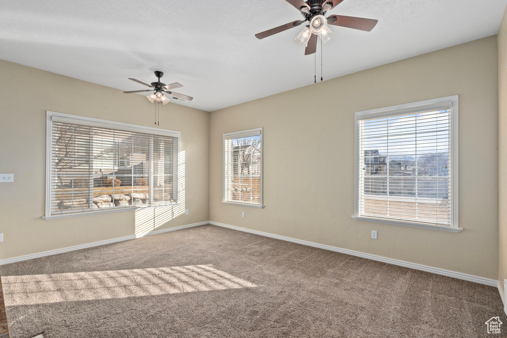 Empty room with ceiling fan and light colored carpet