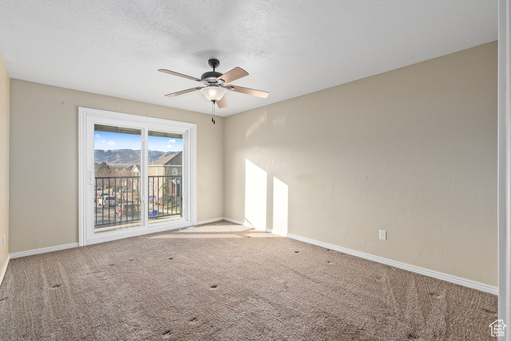 Carpeted spare room with a textured ceiling and ceiling fan