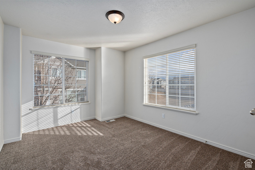 Empty room featuring a textured ceiling and carpet