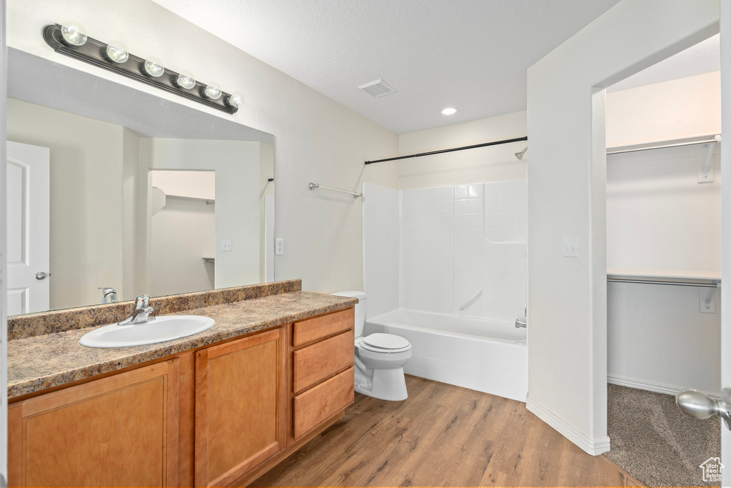 Full bathroom featuring wood-type flooring, vanity, washtub / shower combination, and toilet