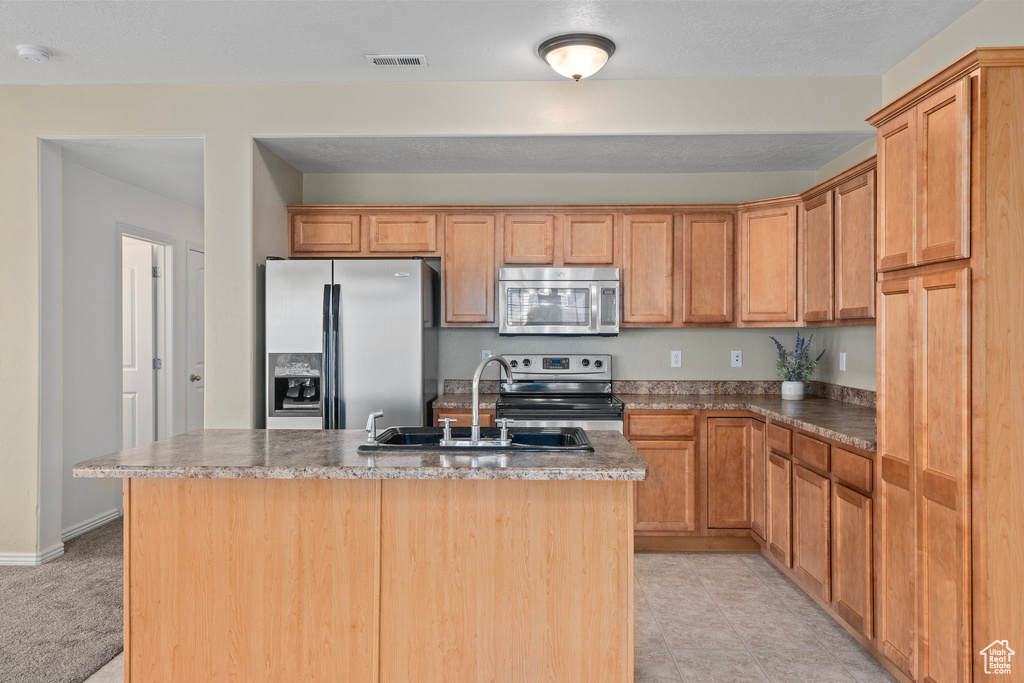 Kitchen featuring stainless steel appliances, sink, a center island with sink, and light tile patterned floors