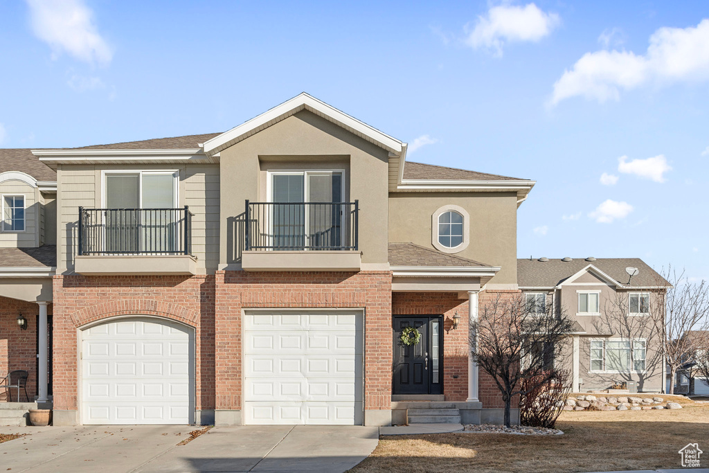 Townhome / multi-family property with a garage and a balcony