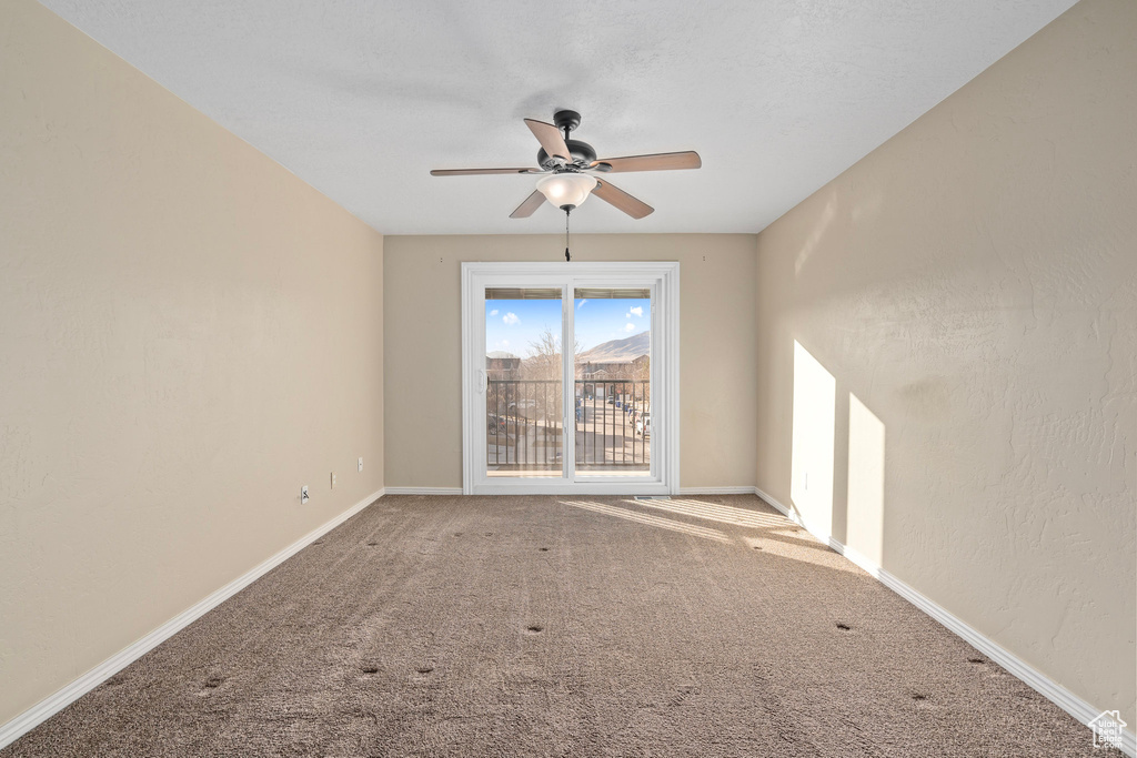 Carpeted empty room featuring ceiling fan